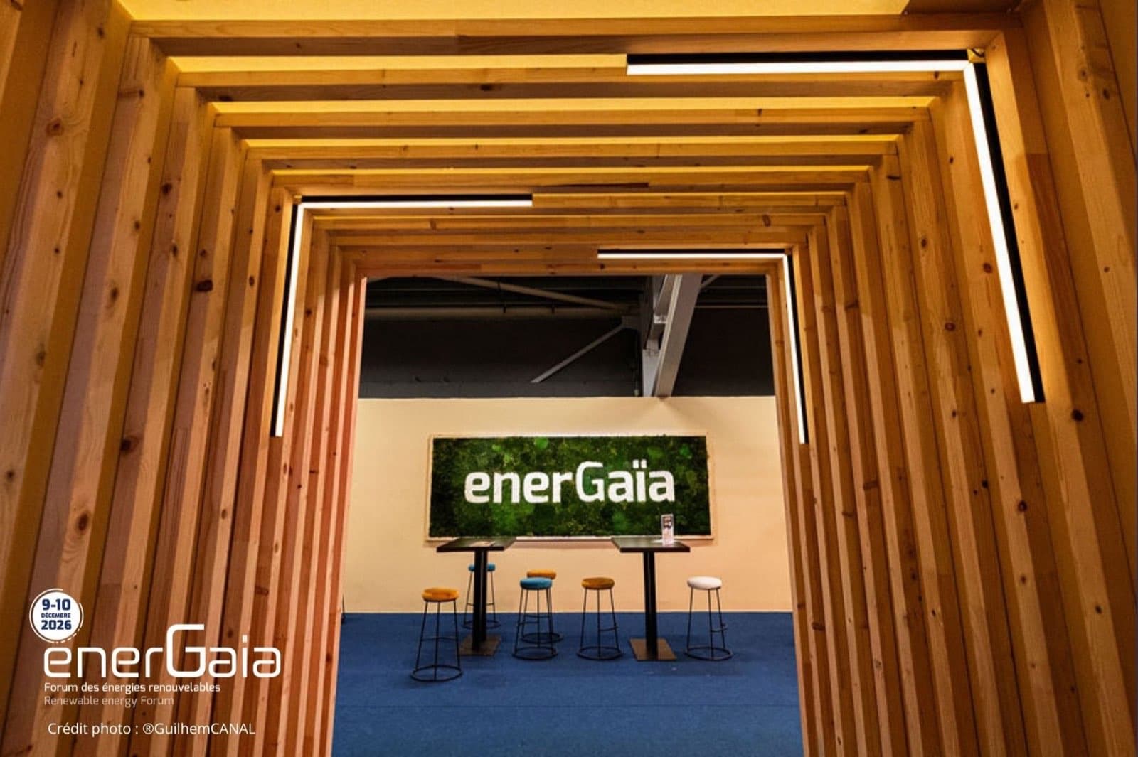 Espacio de encuentro de madera del Foro EnerGaïa, con el muro vegetal y el logotipo de la feria